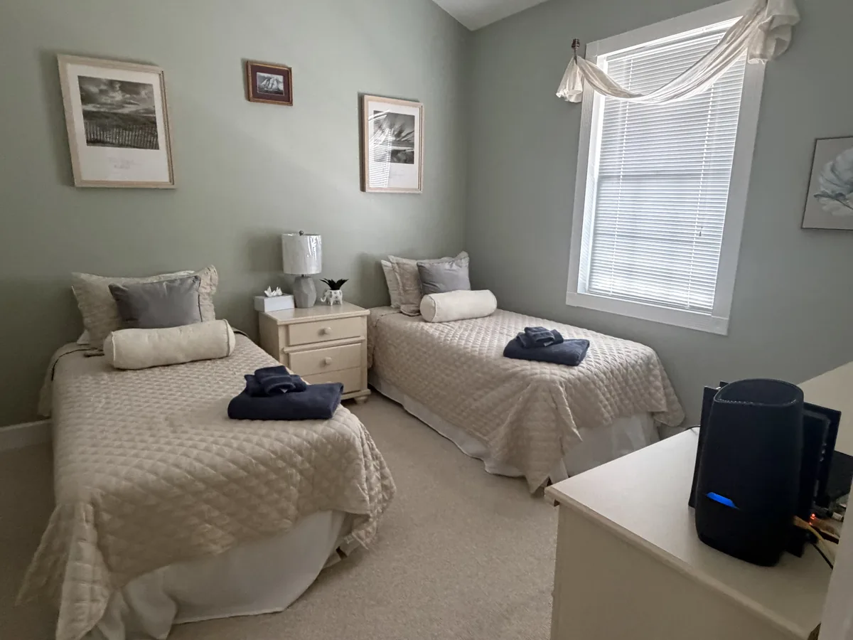 Bedroom with two twin beds made up and folded towels set on each