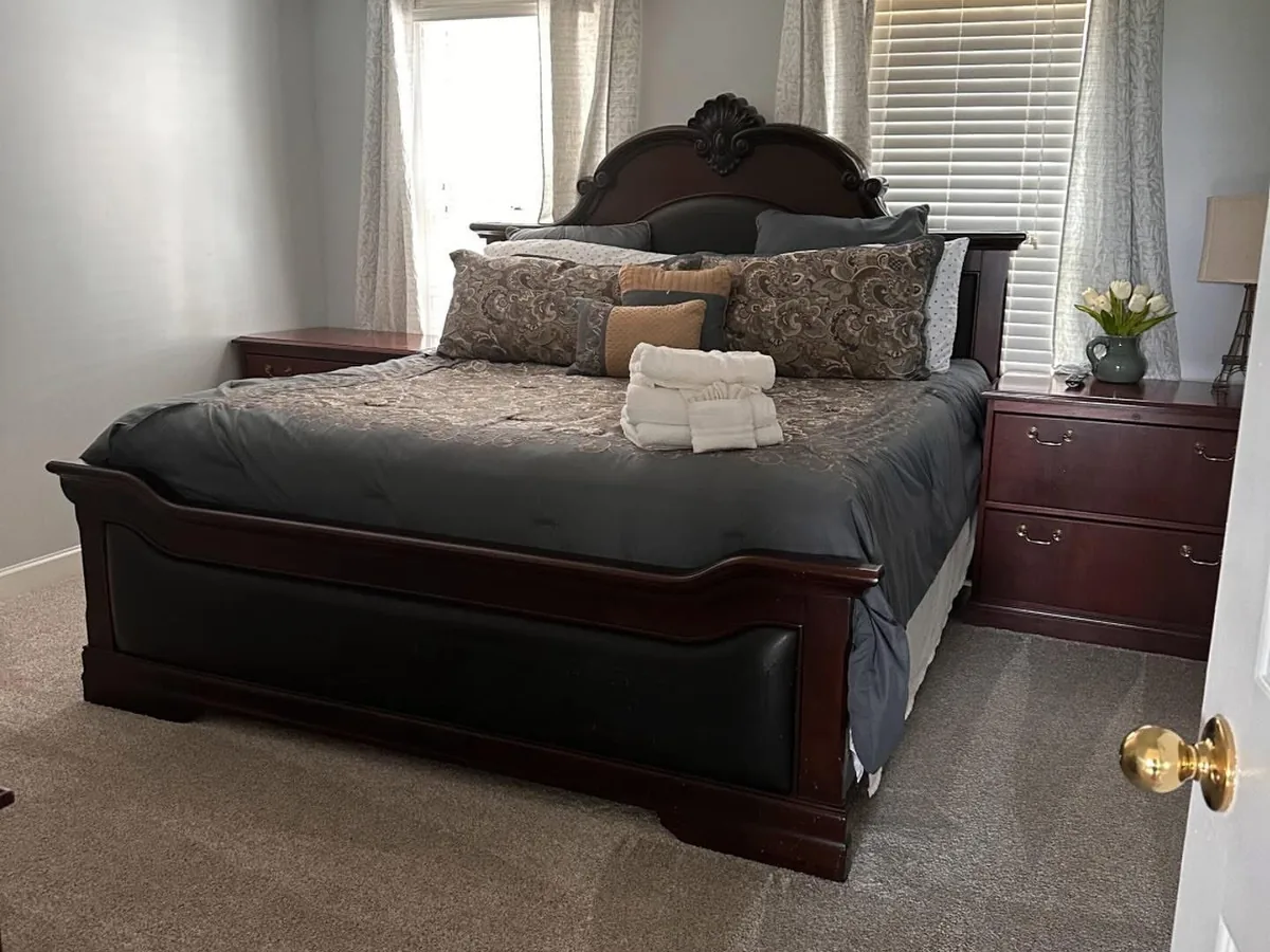 Cleaned bedroom with a dark wood bed, made bedding and folded towels at the foot
