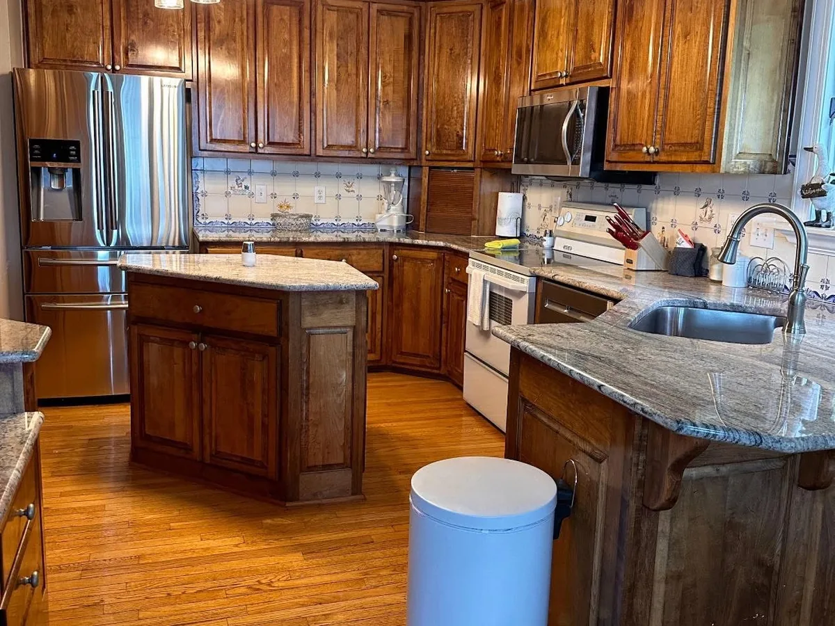 Cleaned wood cabinets, a granite island and a polished sink