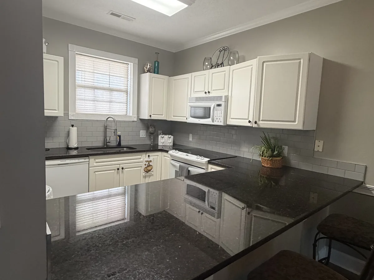 Cleaned white cabinets, dark granite counters and a cleared sink