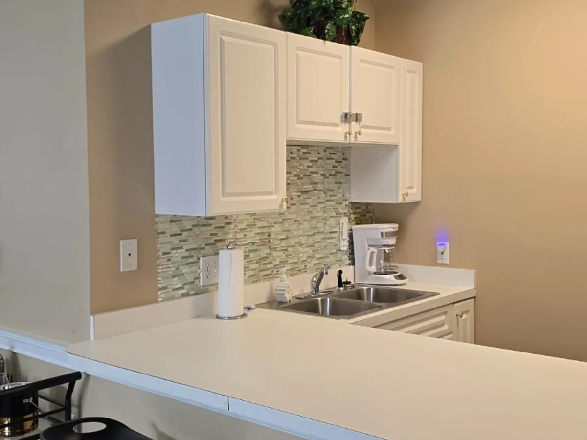 Kitchen with white cabinets, a glass tile backsplash and a wiped countertop