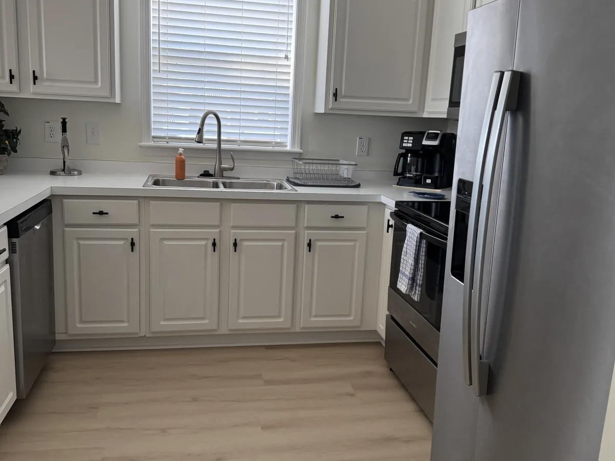 Kitchen with white cabinets, stainless steel refrigerator and range, and a clear countertop
