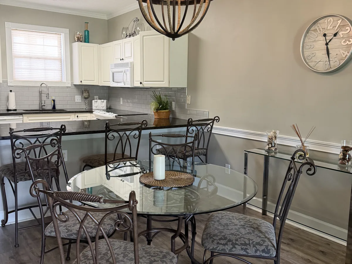 Glass table, wrought iron chairs and white cabinets