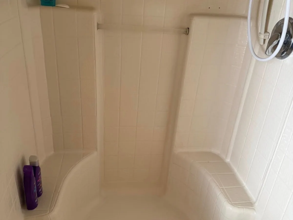 Fiberglass shower corner after cleaning, with the walls and seat scrubbed clean