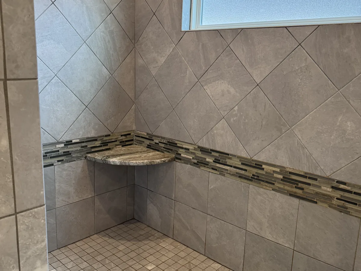 Cleaned tile shower with a glass mosaic border band and scrubbed grout